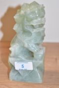 A Chinese carved green stone Dog of Foe, modelled with mouth gaping and front paw resting on a ball,