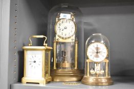 A 20th century brass and glass 400 day anniversary clock, with torsion pendulum, sold together