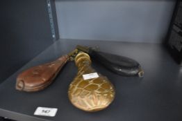 Two Leather and brass shot flasks one containing shot and an ornate powder flask