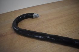 An ebonised walking cane with a cast silver metal tip to the handle in the form of an eagles head
