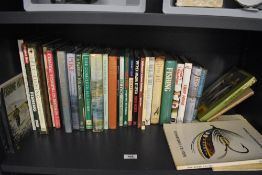 A shelf of over 30 fishing related books the majority are about fly fishing and fly tying