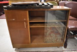 A vintage low bookcase with cupboard to side and sliding glass doors, on shepherds castors, width