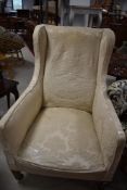 An Edwardian upholstered armchair on tapered legs with brass castors