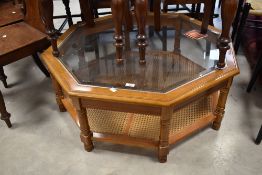 A modern coffee table of octagonal form having glass top and canework undertier, width approx. 95cm
