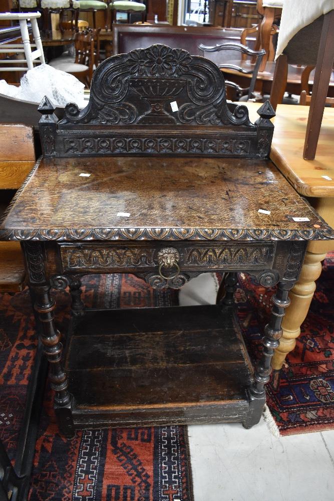 A period oak side table having carved frieze drawer with lion mask handle and carved back panel,