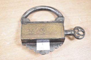 A late 19th to early 20th century Mughal iron and brass padlock, with a screw type key, of ornate