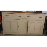 A late 19thC and later cream painted wooden sideboard, the showwood pine surface over two drawers/