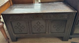 An 18th century oak coffer with a planked rectangular top above a carved three panel front on