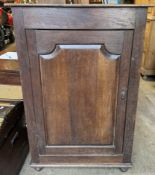 An 18th century oak side cabinet with a planked rectangular top above a shaped cupboard door on