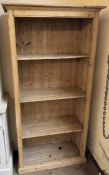 A pine bookcase with a moulded cornice above four shelves and a plinth base, 84.