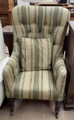 A Victorian upholstered elbow chair with button back on turned legs and casters