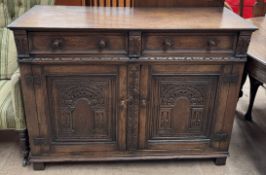 A 20th century oak sideboard with a rectangular top above two drawers and two cupboards on square