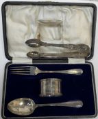 A silver christening set of a spoon fork and napkin ring together with silver sugar nips