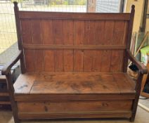 A 19th century pine settle with a planked back and arms above a box seat on square legs,