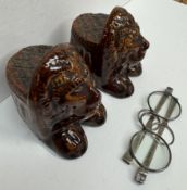 A pair of treacle glazed sash window rests of lion head form together with a pair of white metal