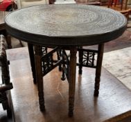An Indian brass topped table with a folding base