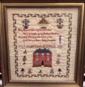 A mid 19th century sampler with a floral border, flowers and a country house by Ann Evans,