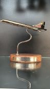 Concorde commemorative metal model on a curved stand with a wood base. Engraved plaque highlights