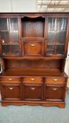 Solid oak china hutch with glass display cabinets and brass hardware. It features lower cabinets,