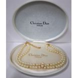 Christian Dior- A 2 strand simulated pearl necklace having a gold tone clasp and CD pendant on chain