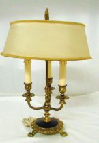 A gilt metal three light table lamp with shade on raised circular base with three claw feet, 50cm (