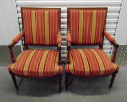 A pair of French upholstered armchairs with turned cylindrical legs and arms