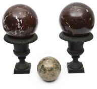 Two polished white veined red marble spheres