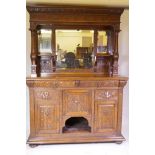 A Victorian carved oak mirror backed sideboard, the upper section with inset bevelled glass, the