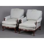 A pair of Edwardian carved mahogany show frame armchairs upholstered in blue material, raised on