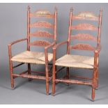 A pair of 19th Century Dutch painted pine ladder back carver chairs with woven rush seats, raised on