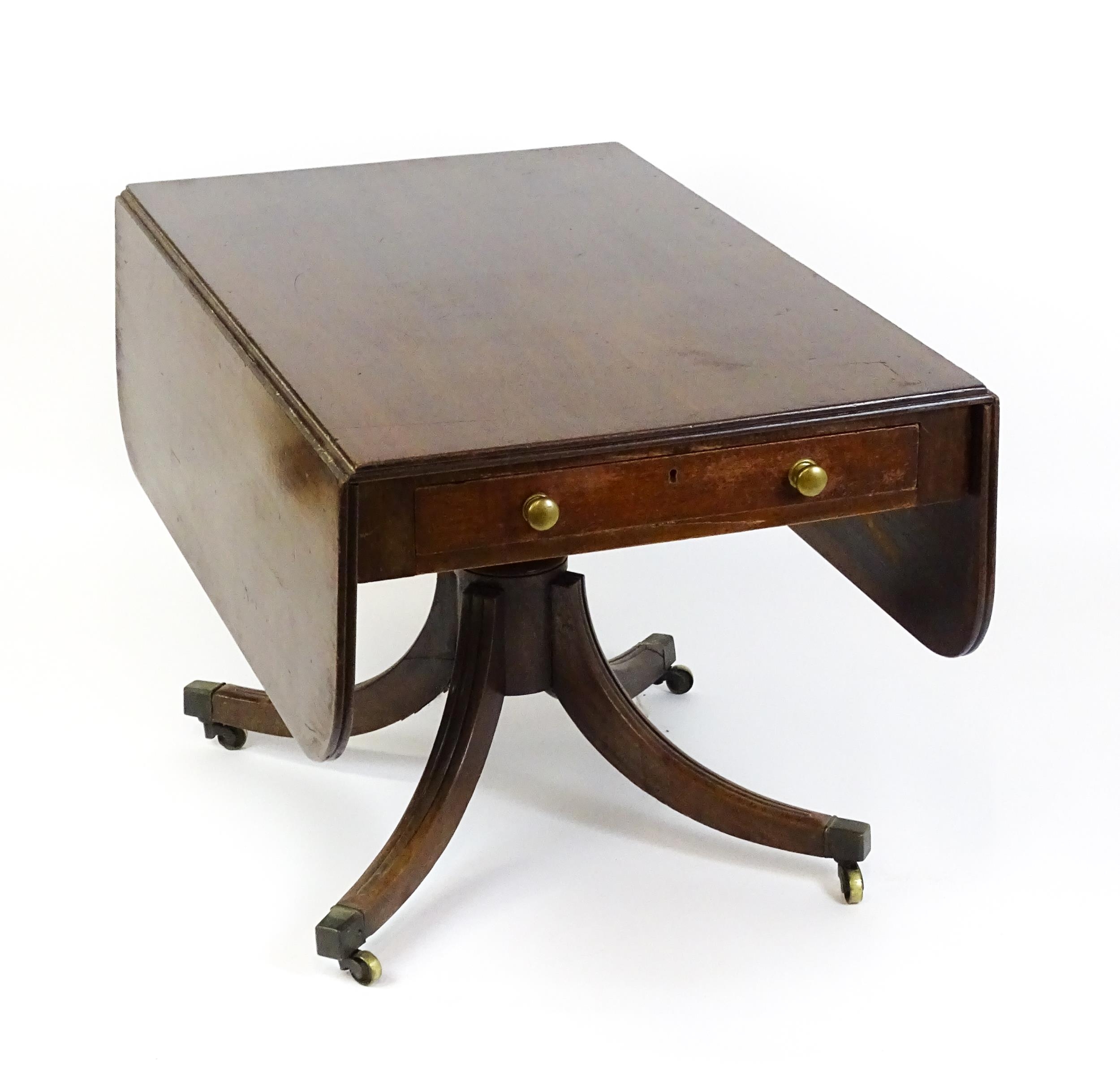 A 19thC mahogany sofa table with two drop leaves above a turned pedestal and four moulded legs