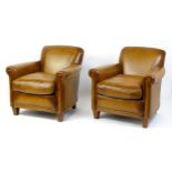 A pair of leather armchairs with scrolled arms and raised on tapering legs. 31" wide x 30" deep x