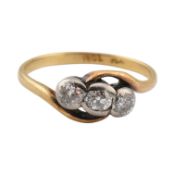 An 18ct gold, platinum and diamond three stone crossover ring set with three bezel mounted diamonds.