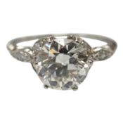 A platinum and single stone diamond set ring, with six stone diamond chip set foliate shoulders, the