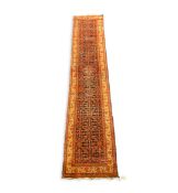 A Malayer runner, with central field of geometric motifs on a black ground, 495 x 102cm PLEASE