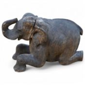 A 19th century Burmese carved teak model of a seated elephant, 41cm wide. Condition - poor tail