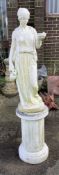 A reconstituted stone garden statue of a female water carrier on fluted pedestal, height 158cm.