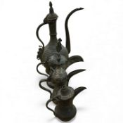 Three Arabic dallahs, two brass, one copper and a copper coffee ewer, 45cm