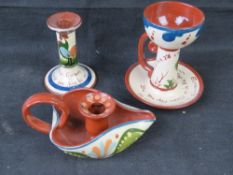 Torquay / Devon motto ware pottery; a candlestick and two chamber sticks,