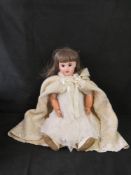 A bisque head doll having jointed limbs, brown eyes, open mouth with teeth and rosy cheeks.