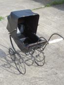A late 19th century dolls pram black painted with matching leather-cloth hood and buttoned seat