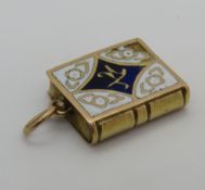 An enamelled charm in the form of an Arabic book, having hidden compartment, no apparent hallmark,