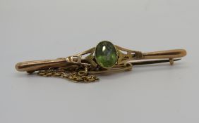 A 9ct gold peridot bar brooch, stamped 9ct, with safety clasp, 2.3g.