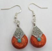 A pair of silver and orange hardstone earrings.