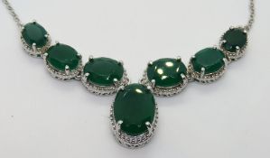 A silver necklace having central articulated panel of six graduated oval cut green stones with