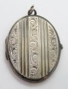 A large white metal locket having floral engraving.