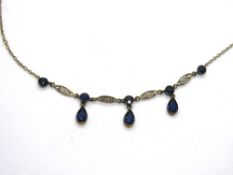 A delightful Edwardian necklace set with three teardrop shaped blue paste stones suspended below a