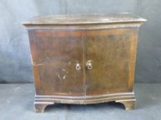 A mid century two door cabinet with a quarter veneered walnut top above a shaped front with egg and