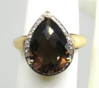 A 9ct gold modern cocktail ring having faceted teardrop cut smoky quartz with gallery of white