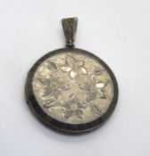 A silver locket having floral engraving to front.